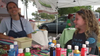 Mieke Toland and Audrey Thompson paint pictures using produce as their brushes and stencils at the Burlington Downtown Farmer's Market.