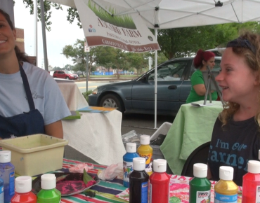 Mieke Toland and Audrey Thompson paint pictures using produce as their brushes and stencils at the Burlington Downtown Farmer's Market.